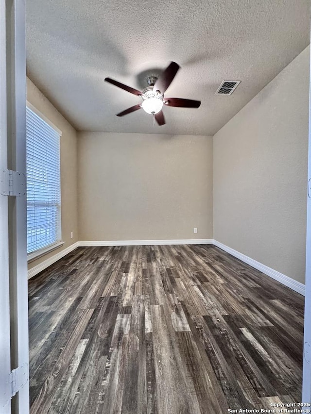 unfurnished room featuring baseboards, visible vents, and dark wood finished floors