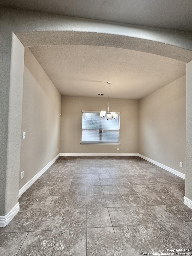 unfurnished dining area with a textured ceiling, baseboards, and an inviting chandelier