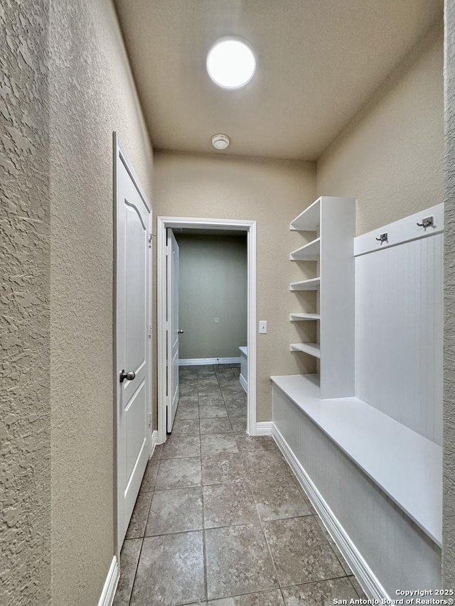 mudroom featuring a textured wall and baseboards