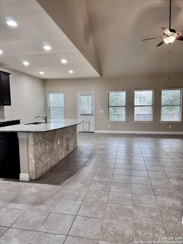 kitchen with open floor plan, a sink, and light stone countertops