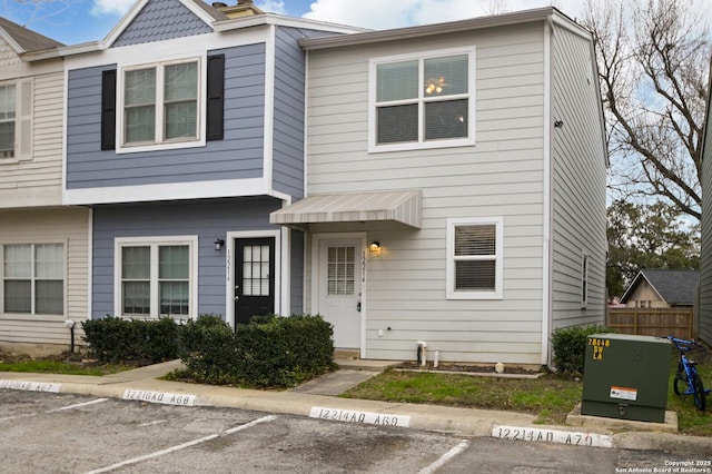 view of property with uncovered parking and fence