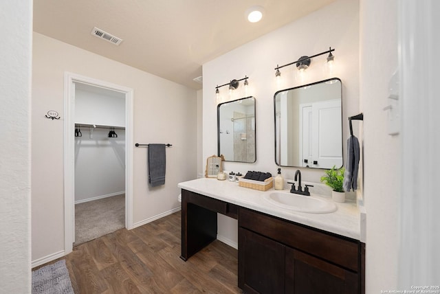 full bath featuring baseboards, visible vents, wood finished floors, a walk in closet, and vanity