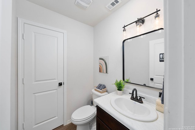 half bath with visible vents, vanity, and toilet