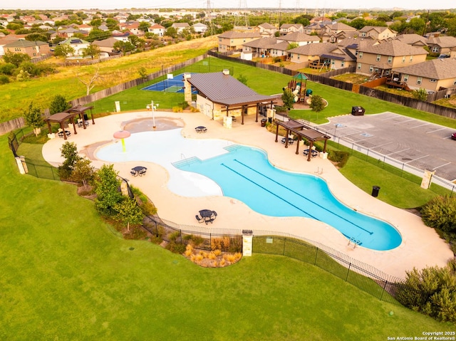 community pool featuring a patio, a yard, fence, and a residential view