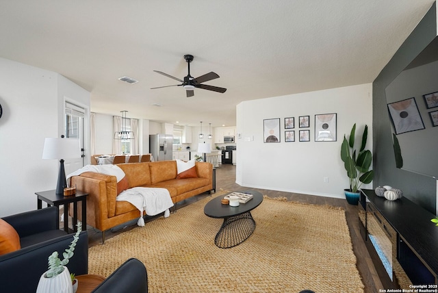 living area with baseboards, ceiling fan, visible vents, and wood finished floors