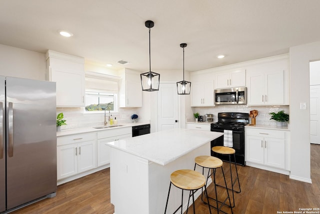 kitchen with a center island, light countertops, white cabinets, a sink, and black appliances