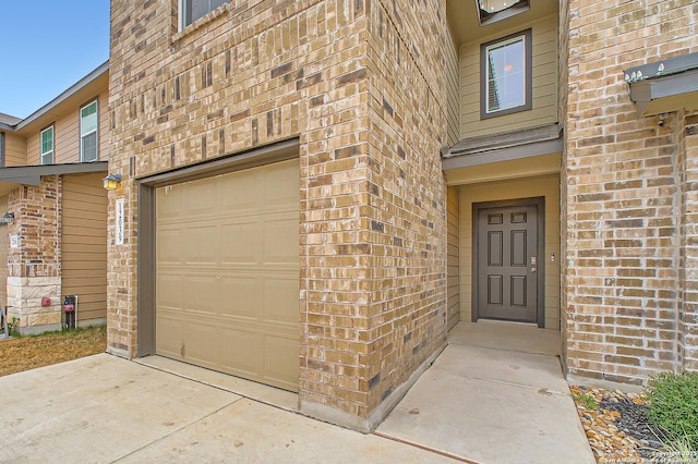 doorway to property featuring concrete driveway and brick siding