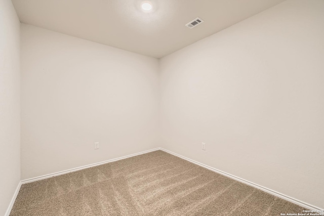 unfurnished room with carpet, visible vents, and baseboards