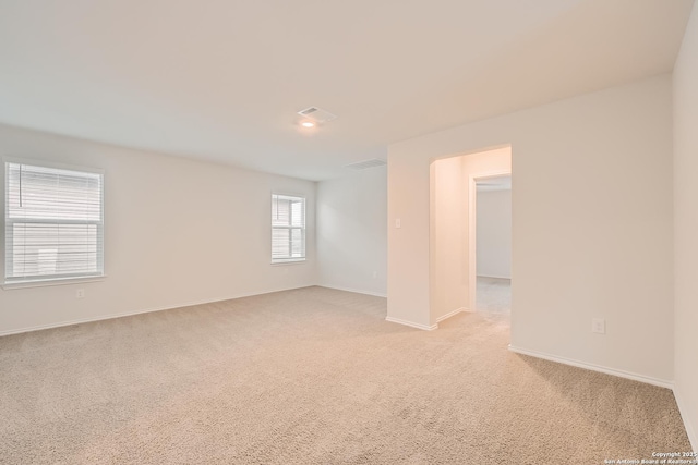 spare room featuring baseboards and light colored carpet