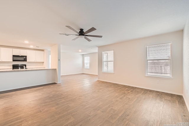 unfurnished living room featuring a ceiling fan, light wood-style flooring, and baseboards