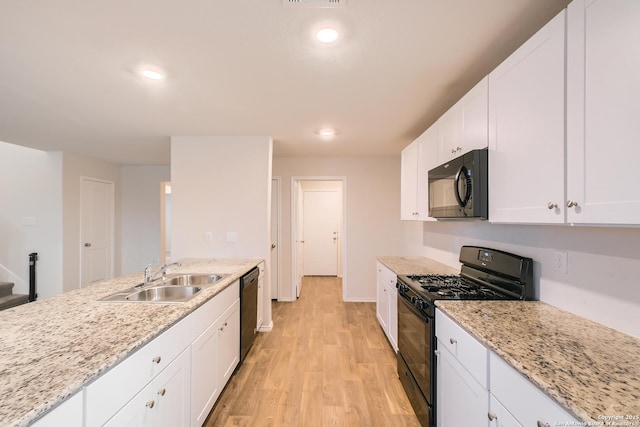 kitchen with light stone counters, a sink, light wood-style floors, white cabinets, and black appliances