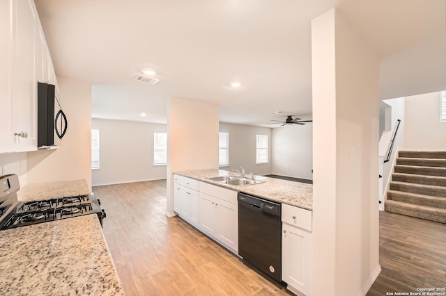 kitchen featuring visible vents, white cabinets, a sink, light stone countertops, and black appliances