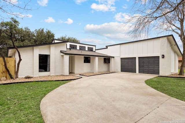 view of front of home with brick siding, concrete driveway, a front yard, fence, and a garage