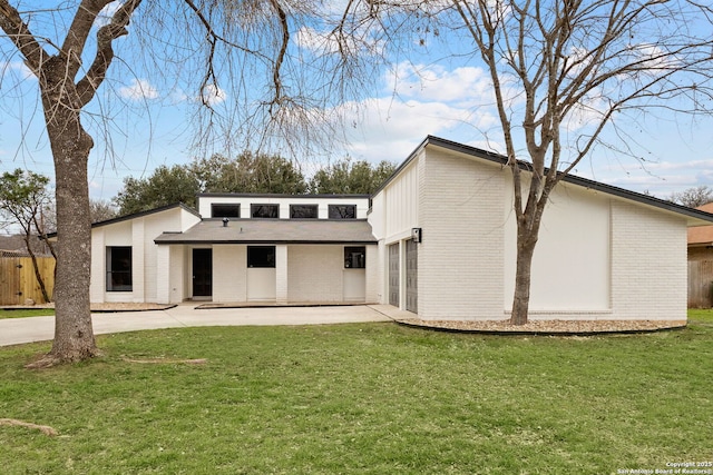 back of property featuring fence, a lawn, a patio, and brick siding