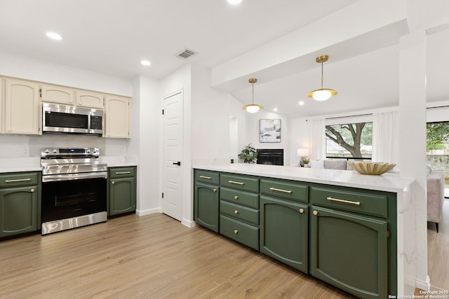 kitchen with light countertops, appliances with stainless steel finishes, hanging light fixtures, and green cabinetry