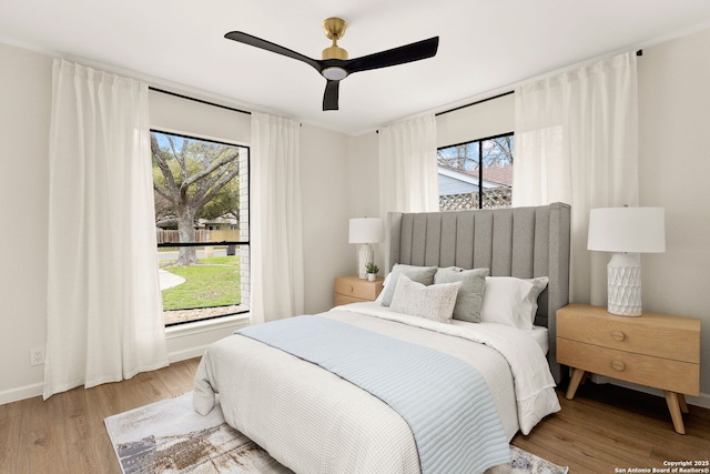 bedroom with baseboards, a ceiling fan, and light wood-style floors