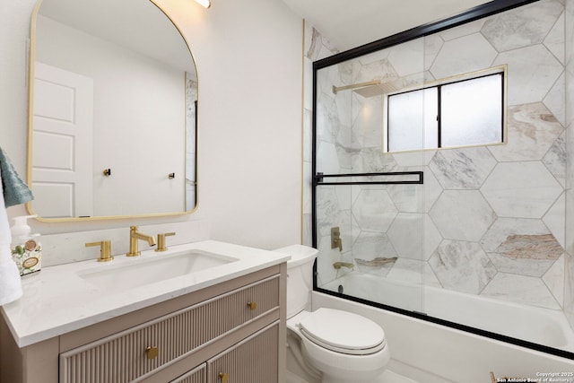 bathroom with toilet, shower / bath combination with glass door, and vanity