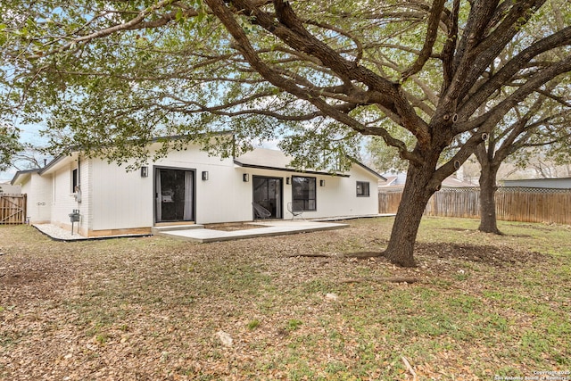 rear view of property with a yard, a patio, and fence