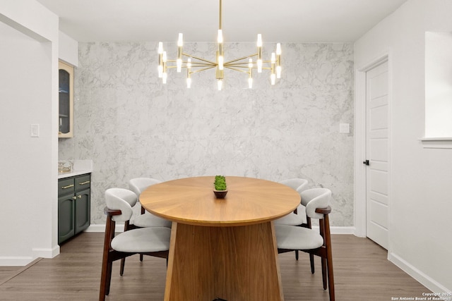 dining room featuring baseboards, wood finished floors, and an inviting chandelier