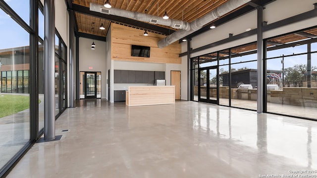 interior space featuring finished concrete flooring, plenty of natural light, and a towering ceiling