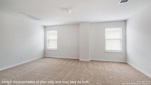 empty room featuring light carpet, visible vents, and a wealth of natural light