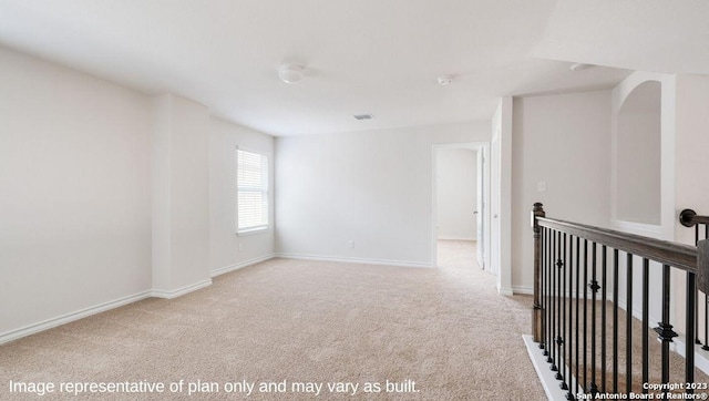 empty room featuring light colored carpet and baseboards