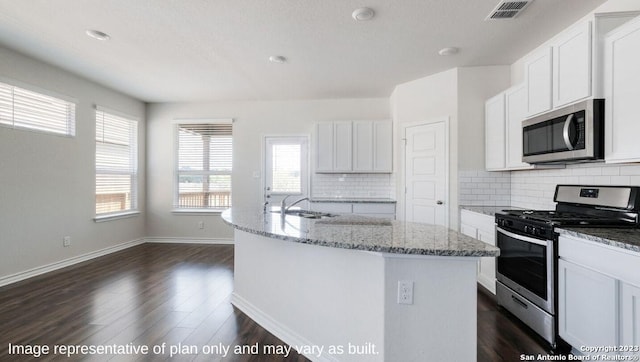 kitchen featuring stainless steel appliances, visible vents, white cabinets, light stone countertops, and a center island with sink