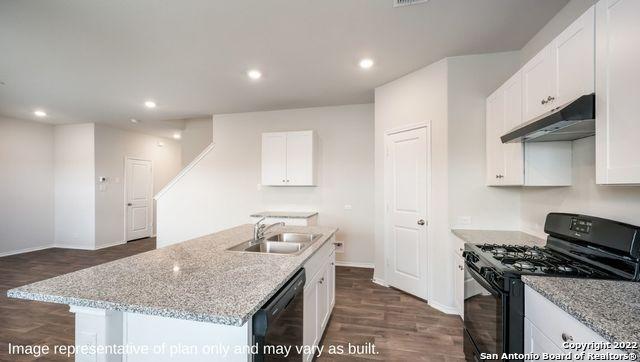 kitchen featuring under cabinet range hood, a sink, white cabinets, black appliances, and an island with sink