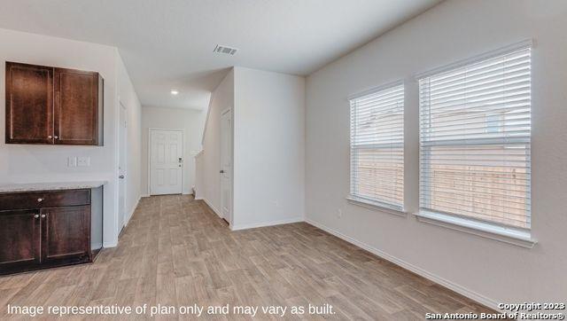 interior space with light wood-type flooring, visible vents, and baseboards