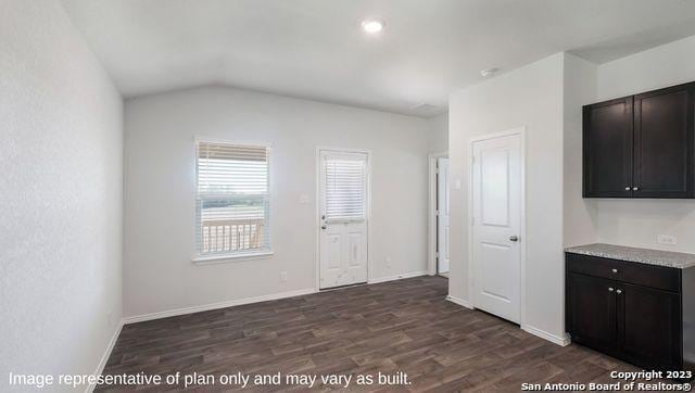 interior space featuring dark wood-type flooring, lofted ceiling, and baseboards