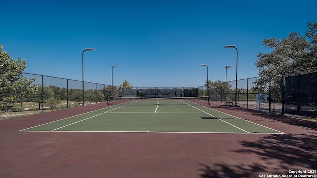 view of tennis court with community basketball court and fence