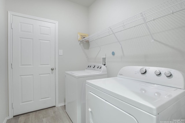 washroom featuring laundry area, light wood finished floors, and separate washer and dryer