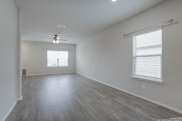 unfurnished room with a ceiling fan, baseboards, visible vents, and wood finished floors