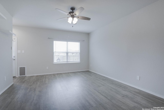 empty room with dark wood-style floors, visible vents, baseboards, and a ceiling fan