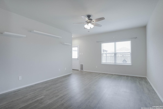 spare room with ceiling fan, dark wood-type flooring, visible vents, and baseboards