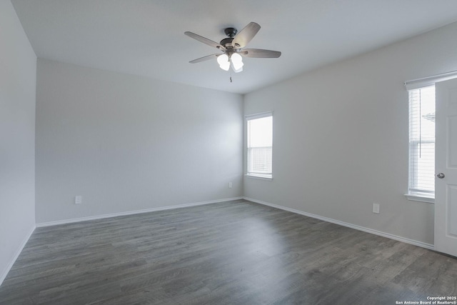 unfurnished room with dark wood finished floors, a ceiling fan, and baseboards