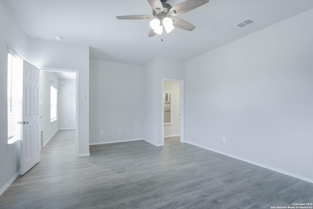 spare room featuring baseboards, visible vents, and wood finished floors