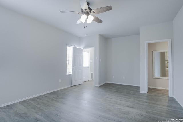 spare room with wood finished floors, a ceiling fan, and baseboards