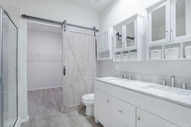 bathroom featuring a walk in closet, double vanity, a sink, and wood finished floors