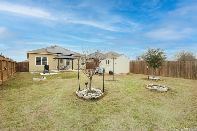 view of yard with an outbuilding, a fenced backyard, and a gazebo