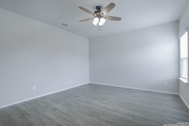 spare room featuring a ceiling fan, baseboards, visible vents, and wood finished floors