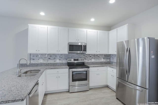 kitchen featuring a peninsula, appliances with stainless steel finishes, a sink, and white cabinetry