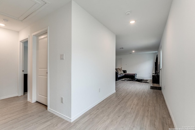 corridor featuring recessed lighting, light wood-type flooring, attic access, and baseboards