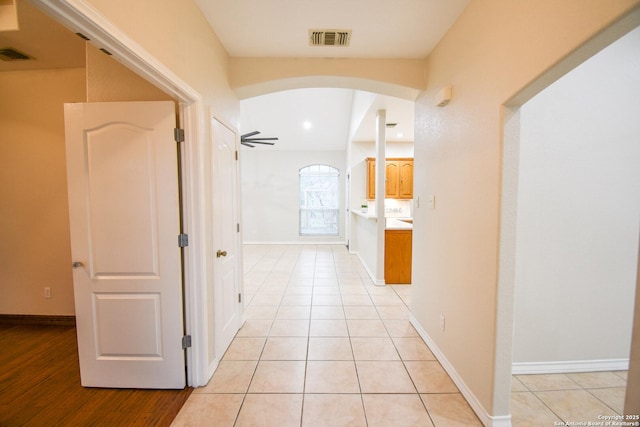 hall featuring light tile patterned floors, arched walkways, and visible vents