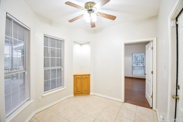 unfurnished room featuring ceiling fan, baseboards, and light tile patterned floors