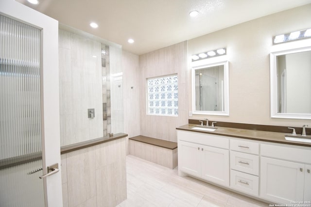 bathroom with a sink, double vanity, walk in shower, and recessed lighting