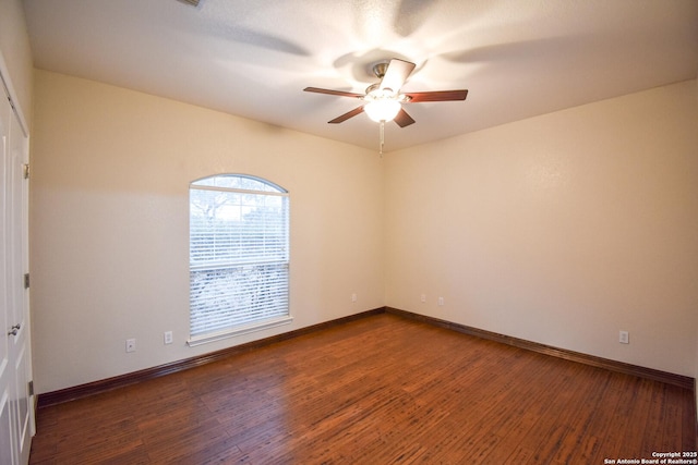 unfurnished room featuring ceiling fan, baseboards, and dark wood-type flooring