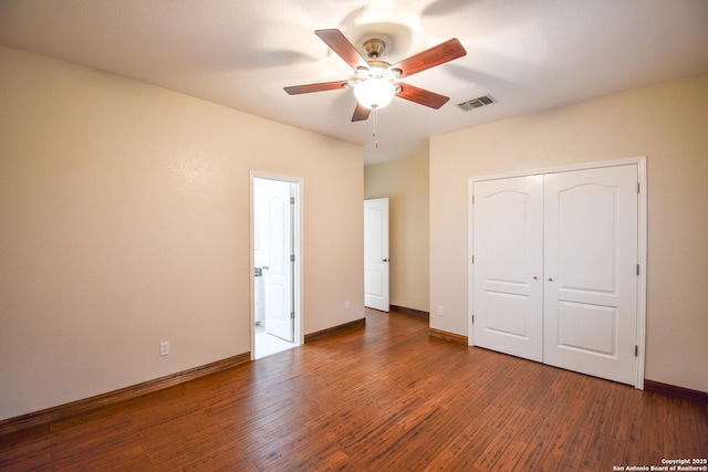 unfurnished bedroom with dark wood-type flooring, a closet, visible vents, and baseboards