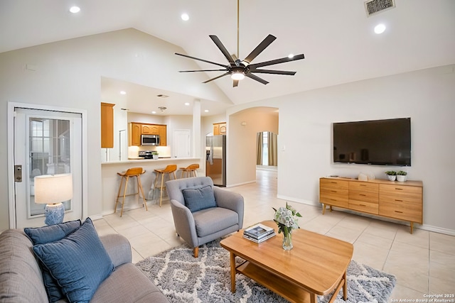 living area with arched walkways, visible vents, a ceiling fan, light tile patterned flooring, and high vaulted ceiling