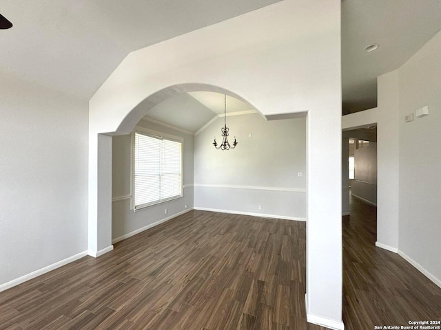 spare room with lofted ceiling, dark wood-style flooring, arched walkways, and baseboards